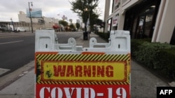 LOS ANGELES, CALIFORNIA - JANUARY 22: A sign reading 'COVID-19 High-Risk Area' is posted on a downtown sidewalk amid a surge in coronavirus infections on January 22, 2021 in Los Angeles, California. One hundred sidewalk warning signs have been…