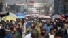 FILE - Afghans walk through a crowded market in Kabul, Afghanistan, Feb. 22, 2020. The country now faces a potential cut in U.S. aid.