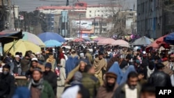 FILE - Afghans walk through a crowded market in Kabul, Afghanistan, Feb. 22, 2020. The country now faces a potential cut in U.S. aid.