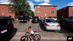 ARCHIVO - Un niño anda en bicicleta durante una marcha organizada por el Colectivo Comunitario de East Colfax para abordar los problemas crónicos en edificios ocupados por personas desplazadas de Centroamérica y Sudamérica, el 3 de septiembre de 2024, en Aurora, Colorado.