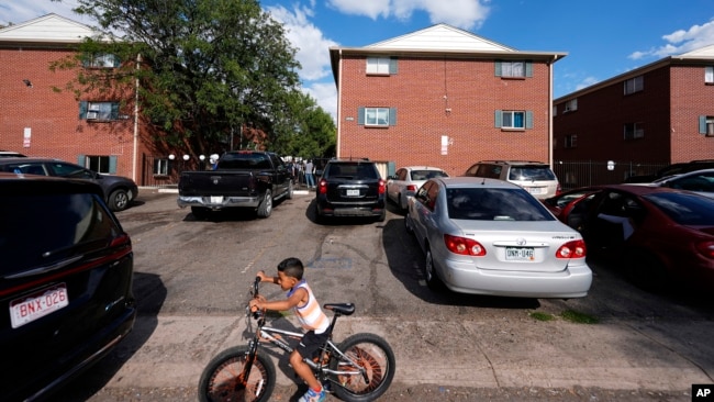 ARCHIVO - Un niño anda en bicicleta durante una marcha organizada por el Colectivo Comunitario de East Colfax para abordar los problemas crónicos en edificios ocupados por personas desplazadas de Centroamérica y Sudamérica, el 3 de septiembre de 2024, en Aurora, Colorado.