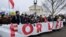 People hold a banner as they walk in front of the Supreme Court building