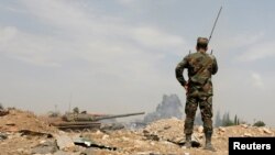 FILE - Soldiers loyal to Syria's President Bashar al-Assad forces are deployed at al-Qadam area near Yarmouk Palestinian camp in Damascus, April 29, 2018.