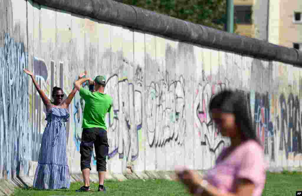 گرفتن عکس یادگاری در کنار بقایای دیوار برلین در سالگرد شصتمین سال ساخت آن در برلین، آلمان