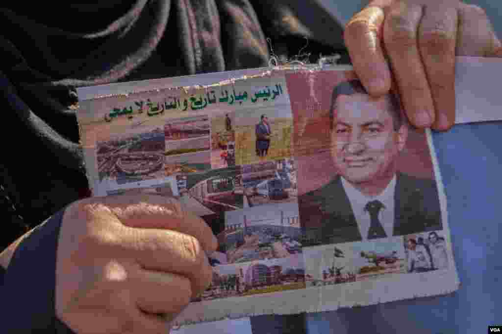 A mourner holds a card with pictures depicting Egypt&#39;s modernization. In his three decades as president, Mubarak initiated major infrastructure projects such as Cairo&#39;s Ring Road, the capital&#39;s subway system, and other projects. (Hamada Elrasam/VOA)