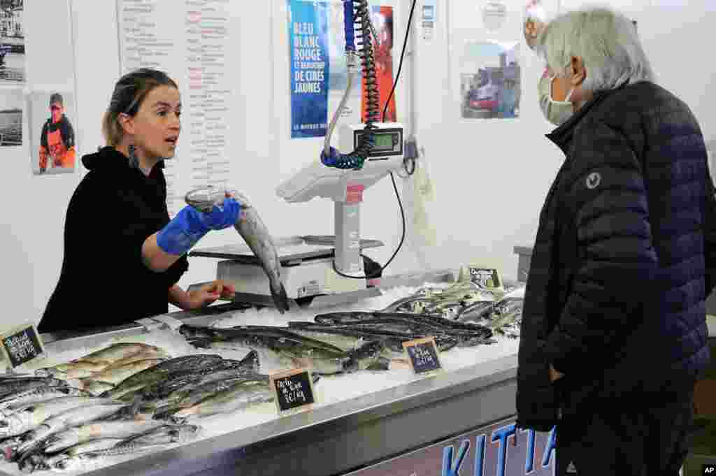 زن ماهی فروش و یک مشتری در جنوب فرانسه. آنها با رعایت فاصله اجتماعی داد و ستد می&zwnj;کنند. فرانسه قصد دارد کم کم برخی مشاغل را بازگشایی کند.&nbsp;