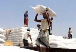FILE - Men deliver U.N. World Food Program aid in Aslam, Hajjah, Yemen, Sept. 21, 2018.