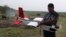 FILE - A mahout walks past with an elephant used for tourist rides as  Remo Peduzzi, Managing Director, Research Drones LLC Switzerland prepares to fly an unmanned aircraft or drone at the Kaziranga National Park at Kaziranga in Assam state, India, April 8, 2013. 