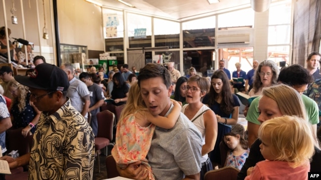 Survivors and churchgoers sing during a Sunday church service held by Pastor Brown of Lahaina's Grace Baptist Church, at Maui Coffee Attic in Wailuku, central Maui, Hawaii on August 13, 2023.