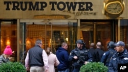 A heavily-armed New York City police officer stands guard outside the Fifth Avenue., public entrance to Trump Tower, Nov. 15, 2016, in New York.