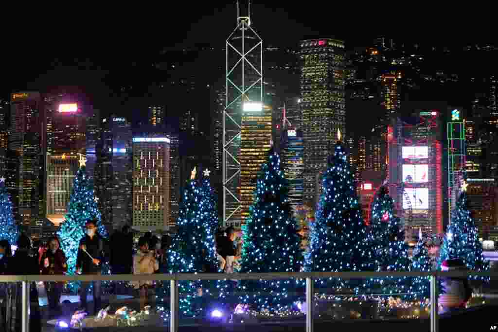 People wearing protective masks take photographs of Christmas trees and holiday decorations in Hong Kong.