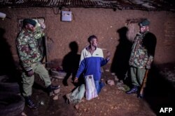 Security officers arrests a man selling alcohol door to door during curfew hours in Kisumu, western Kenya, March 29, 2020.