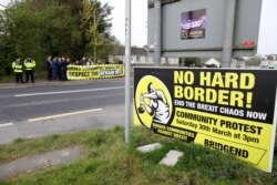 FILE - Protesters against Brexit and the possible imposition of any hard border between Northern Ireland and Ireland gather with a banner near the Irish village of Bridge End, April 18, 2019.