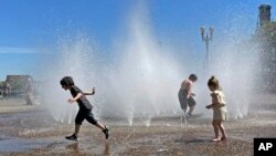 Anak-anak menyejukkan diri dengan bermain di air mancur di pusat kota Portland, Oregon, Jumat, 12 Mei 2023. (AP/Claire Rush)