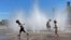 Anak-anak menyejukkan diri dengan bermain di air mancur di pusat kota Portland, Oregon, Jumat, 12 Mei 2023. (AP/Claire Rush)