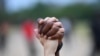 FILE - A man and a woman hold hands aloft in Hyde Park during a "Black Lives Matter" protest following the death of George Floyd who died in police custody in Minneapolis, London, Britain, June 3, 2020.