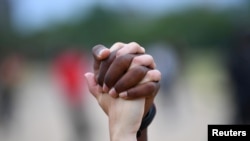 FILE - A man and a woman hold hands aloft in Hyde Park during a "Black Lives Matter" protest following the death of George Floyd who died in police custody in Minneapolis, London, Britain, June 3, 2020.