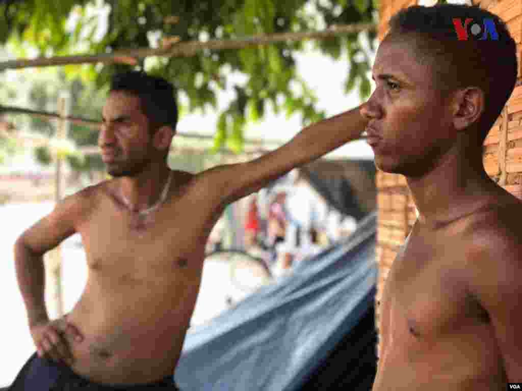 Dos hombre pasan el rato a las afuera del refugio improvisado&nbsp;creado por venezolanos en el vecindario Jardim Floresta, fronterizo de Brasil. Foto: Celia Mendoza - VOA