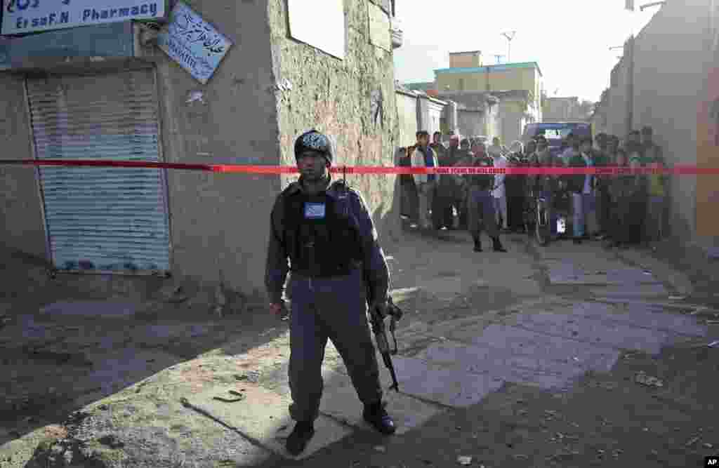 An Afghan policeman stands guard at the site of a roadside bomb explosion, in Kabul, Oct. 21, 2014. 