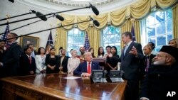 President Donald Trump listens to Ambassador-at-Large for International Religious Freedom Sam Brownback, standing right center, as he meets with survivors of religious persecution in the Oval Office of the White House, July 17, 2019.