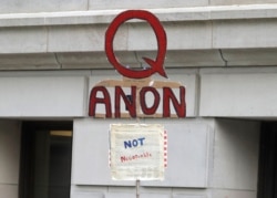 FILE - In this May 14, 2020, photo, a person carries a sign supporting QAnon at a protest rally in Olympia, Wash.