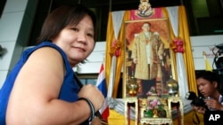 FILE - Chiranuch Premchaiporn, director of Prachatai website, walks past a portrait of King Bhumibol Adulyadej at the criminal court in Bangkok. Thailand's Supreme Court, Dec. 23, 2015, upheld the 2012 conviction of the webmaster for not acting quickly enough to delete online comments deemed insulting to the monarchy.