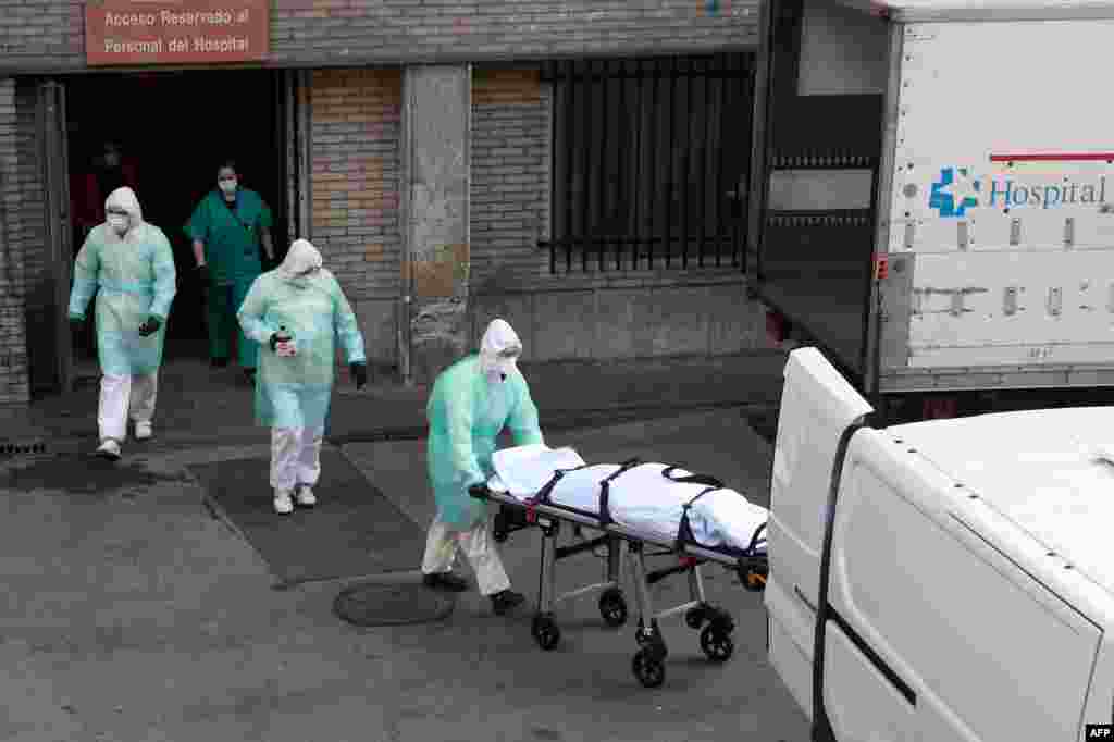 A health worker carries a body on a stretcher outside Gregorio Maranon hospital in Madrid, Spain. Spain joined Italy in seeing its death toll from the coronavirus pandemic surpass that of what China reported.