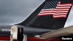 El expresidente de EEUU Donald Trump aparece en la puerta de su avión particular con la bandera estadounidense en la cola, al llegar a Aberdeen, Escocia, el 1 de mayo de 2023.