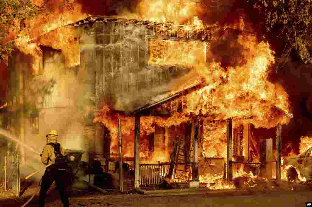 A firefighter puts out the Sugar Fire, part of the Beckwourth Complex Fire, in Doyle, California, July 10, 2021.