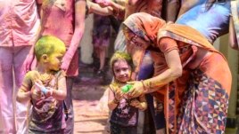 A mother teaches to her children to use water guns during Holi, the spring festival of colours, in Hyderabad on March 29, 2021.