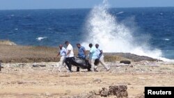 Forensic workers carry a bag containing the body of a person who was found at the shore, near Willemstad, Curacao, Jan. 10, 2018. 