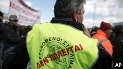 FILE - A dock worker with a "Not for sale" sign on his vest takes part in a protest against government plans to further privatize the harbor of Piraeus, Greece.