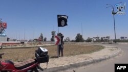 Seorang militan ISIS memasang bendera di sebuah jalanan di kota Ramadi (foto: dok).