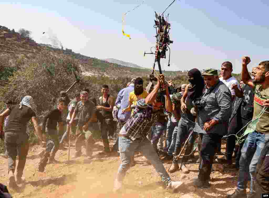 A Palestinian protester smashes an Israeli drone that reportedly fell because of a technical failure, during a demonstration against settlements in the West Bank village of Beita.