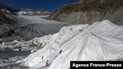 A man works at the Rhone Glacier partially covered with insulating foam to prevent it from melting due to global warming near Gletsch, Switzerland, Oct. 27, 2021. 
