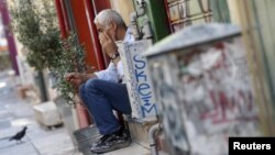 A vendor sits on the steps in front of his shop in central Athens, Greece, July 13, 2015.