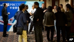 Relatives of Chinese passengers aboard the missing Malaysia Airlines flight MH370 chat outside the conference room during a briefing held by Malaysia officials at a hotel in Beijing, China, April 11, 2014.