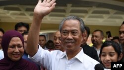 Mantan menteri dalam negeri Malaysia, Muhyiddin Yassin (tengah) didampingi istrinya, Noraini Abdul Rahman (kiri) dan keluarga sebelum konferensi pers di kediamannya di Kuala Lumpur, Sabtu, 29 Februari 2020. (Foto: AFP)