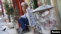 Un vendeur sur les marches devant son magasin dans le centre d'Athènes, en Grèce, le 13 juillet 2015.