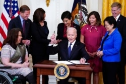 President Joe Biden hands out a pen after signing the COVID-19 Hate Crimes Act, in the East Room of the White House, May 20, 2021.