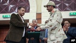 Pemimpin gerakan pro-demokrasi Sudan Ahmad al-Rabiah (kiri) berjabat tangan dengan pemimpin militer Jenderal Mohammed Hamdan Dagalo pasca penandatangan kesepakatan di Khartoum, Sudan, Rabu (17/7). 