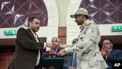 Le général Mohammed Hamdan Dagalo, et le leader du mouvement pour la démocratie au Soudan, Ahmad al-Rabiah, se serrent la main après la signature à Khartoum d'un document de partage du pouvoir au Soudan, mercredi 17 juillet 2019. 