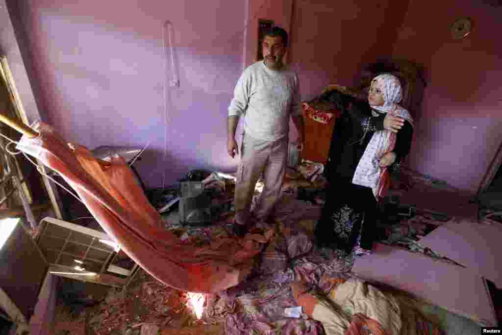 People examine damage inflicted on their house by a car bomb attack in al-Mashtal, Baghdad, March 19, 2013.