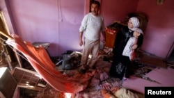 ຜູ້ຄົນພາກັນກວດເບິ່ງຄວາມເສຍຫາຍຕໍ່ເຮືອນຊານເຂົາເຈົ້າ ຍ້ອນການວາງລະເບີດລົດ ທີ່ໃຊ້ໂຈມຕີໃນເມືອງ al-Mashtal ໃນນະຄອນ Baghdad ຂອງອີຣັກ ໃນວັນທີ 19 ມີນາ 2013.