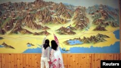FILE - People point to a map on a wall in Mount Kumgang resort in Kumgang, Sept. 1, 2011. 