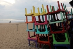 FILE - Stacked-up tables are pictured outside a beach restaurant closed amid the spread of COVID-19, at Seminyak Beach in Bali, Indonesia, March 23, 2020.
