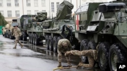 FILE - U.S. soldiers perform maintenance on an armored vehicle during a stop of their convoy in Prague, Czech Republic, March 31, 2015. The convoy started in Estonia and also passed through Latvia, Lithuania and Poland before returning to a German base.