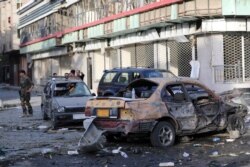 An Afghan national army soldier, left, stands guard near debris following an attack in Kabul, Aug. 4, 2021.