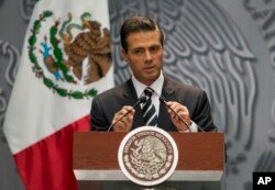 FILE - President Enrique Pena Nieto adjusts his microphones as he arrives at a press conference to express his outrage over the recent disappearance of 43 students in Guerrero State following a violent confrontation with the police, in Mexico City, Oct. 6, 2014.