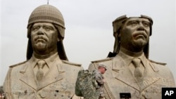 U.S. soldiers walk past two gigantic status of former Iraqi President Saddam Hussein in Baghdad, March 20, 2009.